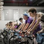 Kolarze na intensywnym treningu spinningowym w sali fitness