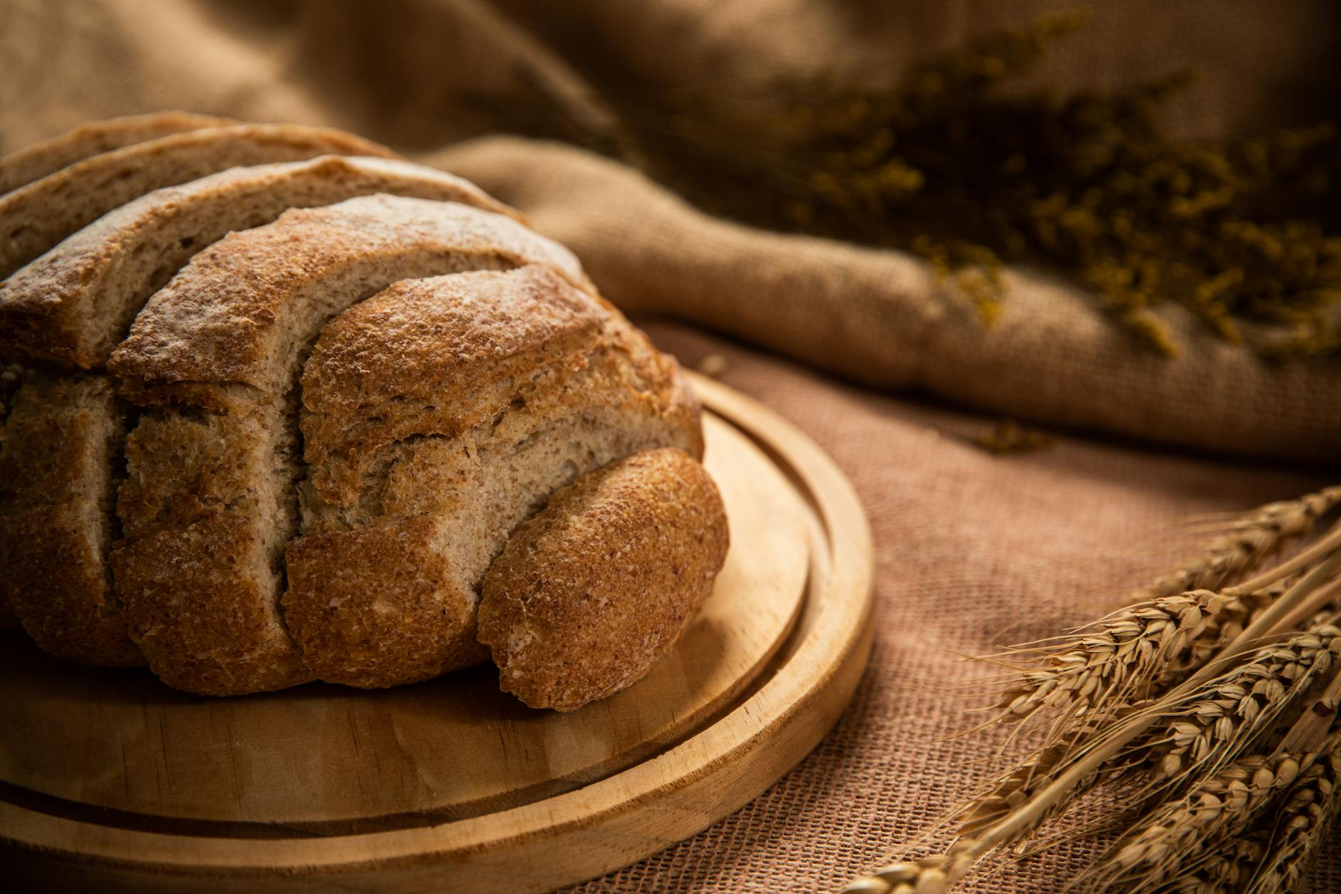 Bochen razowego chleba na desce z kłosami pszenicy w tle