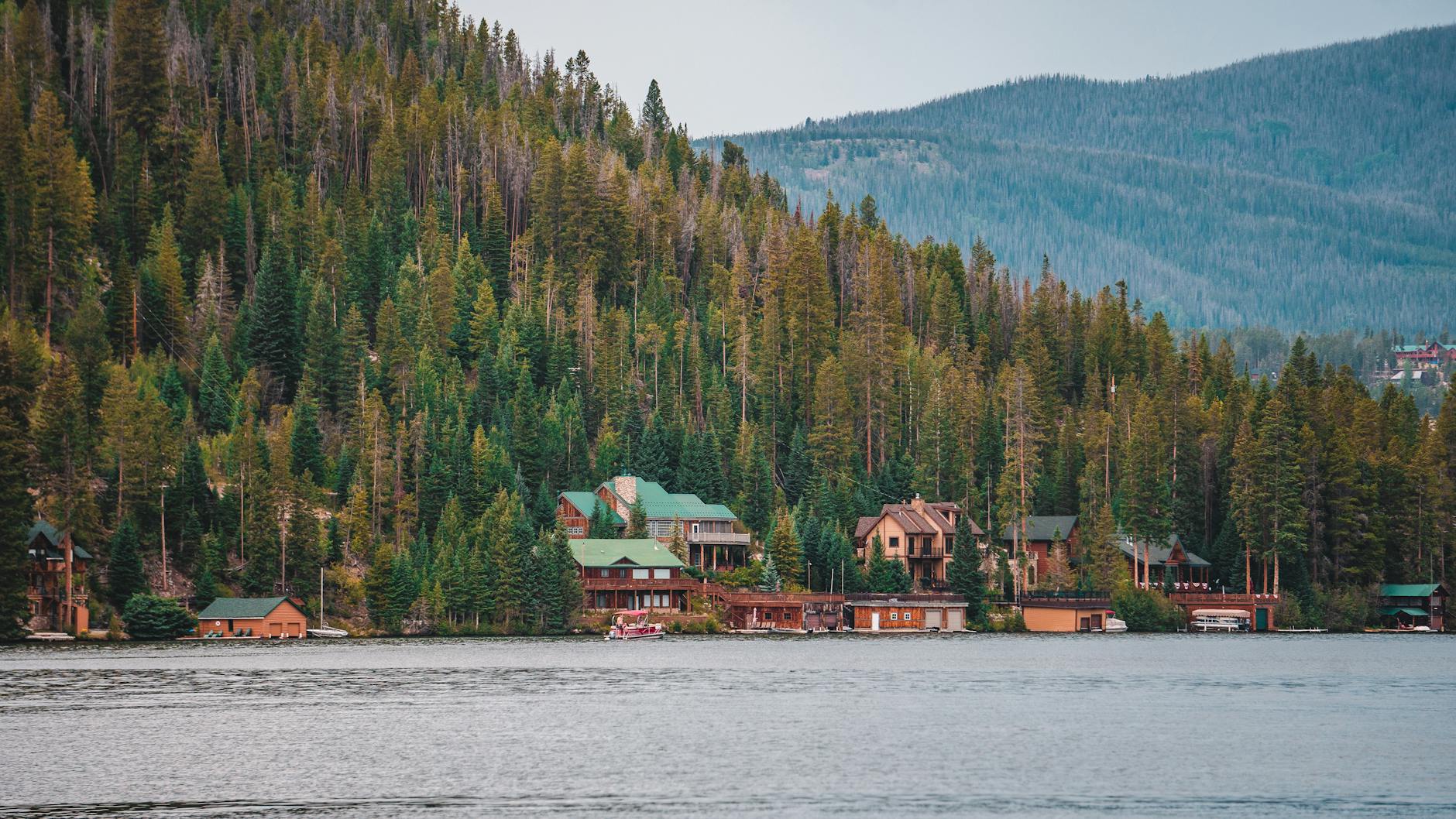 Domki nad jeziorem otoczone gęstym, górskim lasem