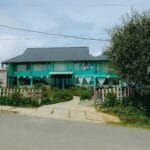 Zielony pensjonat agroturystyczny wśród drzew przy spokojnej wiejskiej drodze