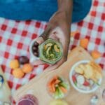 Dłoń trzyma słoik domowego pesto z nerkowców na piknikowym kocu