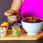 Kobieta przygotowuje pożywną miskę acai z świeżymi owocami