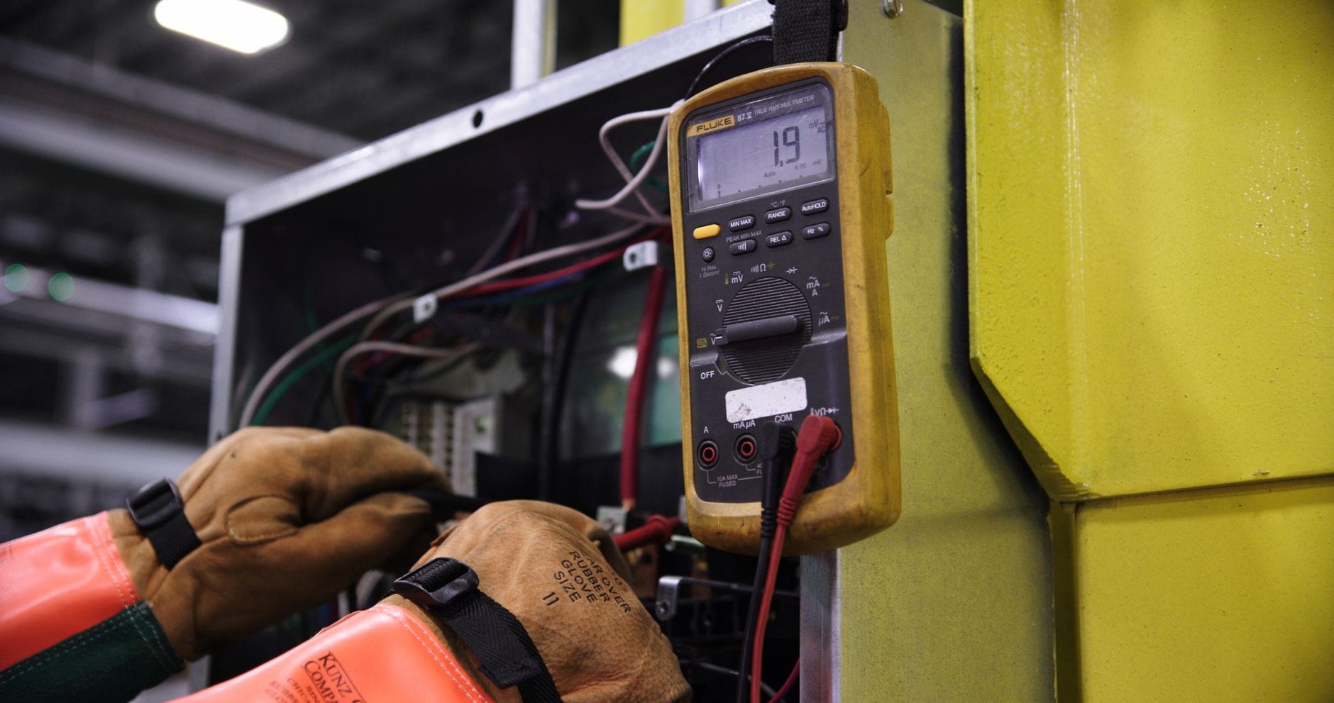 Elektryk mierzy napięcie w przemysłowej rozdzielni elektrycznej