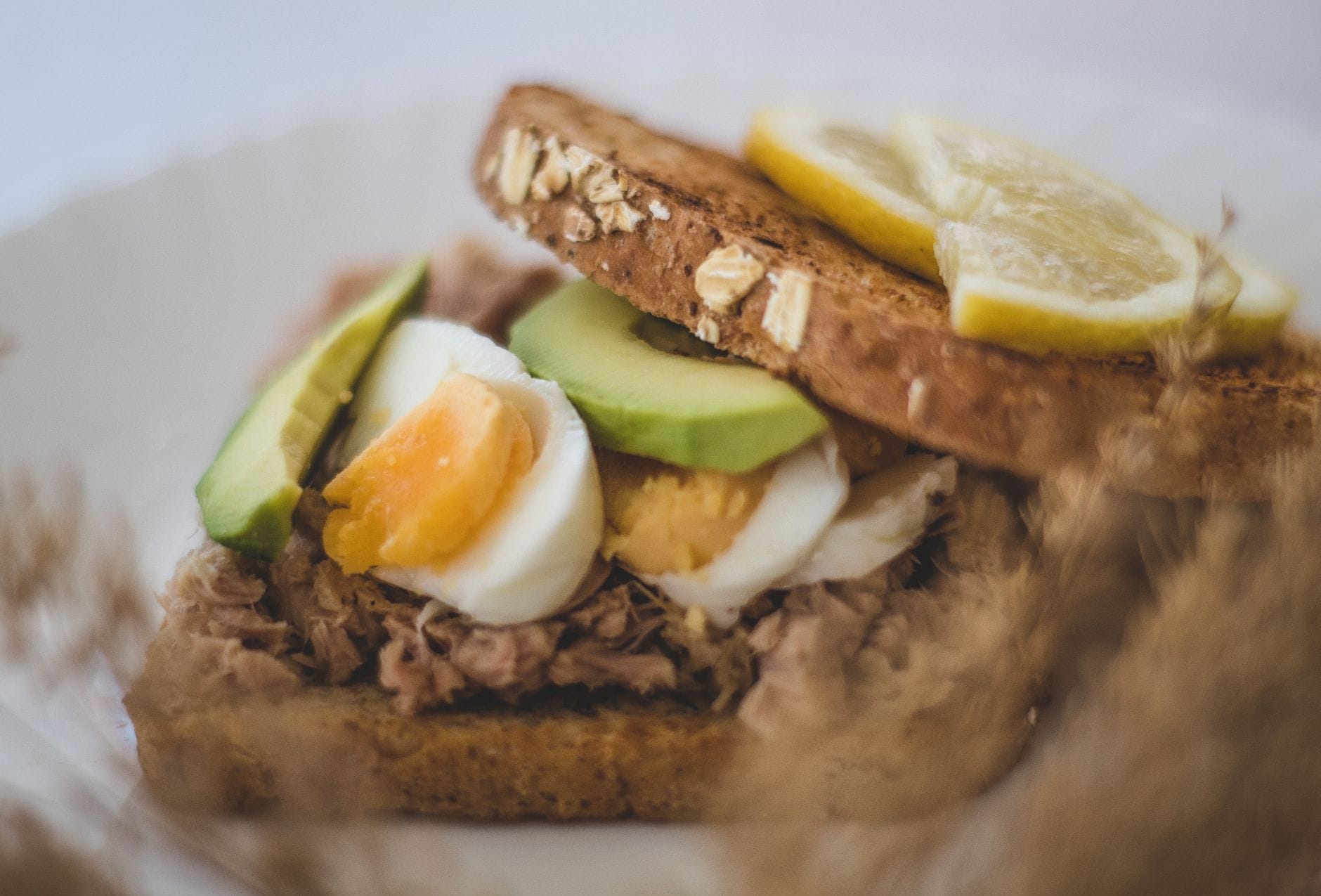 Kanapka z awokado, tuńczykiem i jajkiem oraz plasterkami cytryny