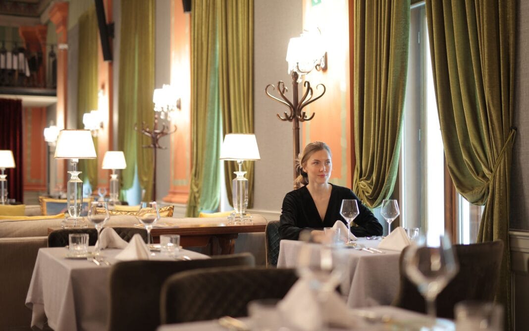 Kobieta samotnie siedząca przy elegancko nakrytym stoliku w restauracji