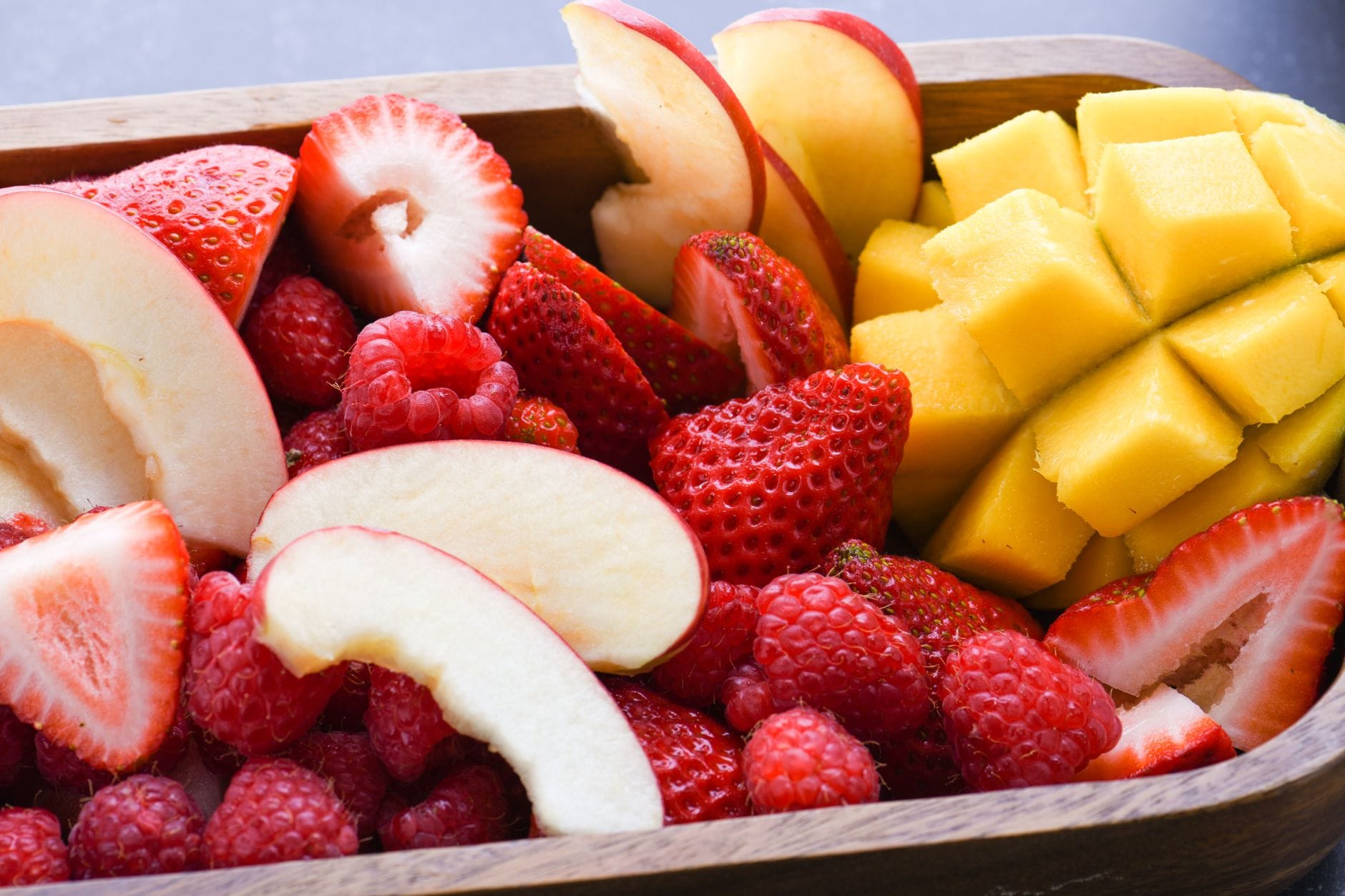 Zbliżenie na pokrojone jabłka, truskawki, maliny i mango